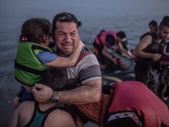 A Syrian refugee holding his son and daughter breaks out in tears of joy after arriving on the shore of the island of Kos in Greece.
